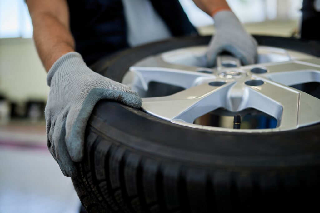 Close-up of a mechanic working with car tire in auto repair shop.