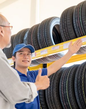 Asian worker of auto parts shop explain and suggest good quality tire to senior customer