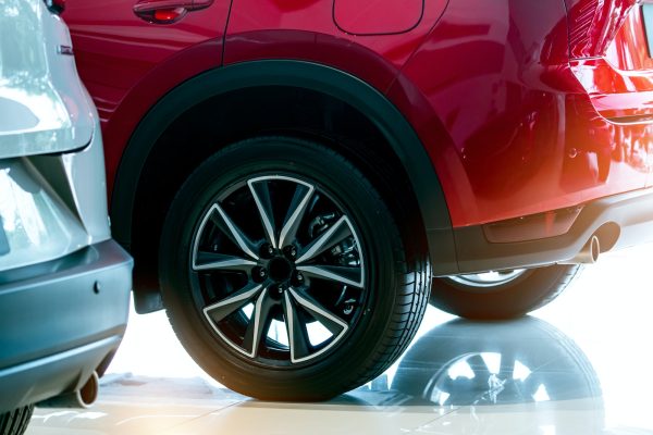 Closeup wheel of red car parked in showroom. Wheel and tire of new car. Car dealership business